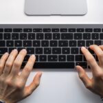 Tilde Mac Tastatur – Finger auf Apple Magic Keyboard beim Eingeben des Tilde-Zeichens