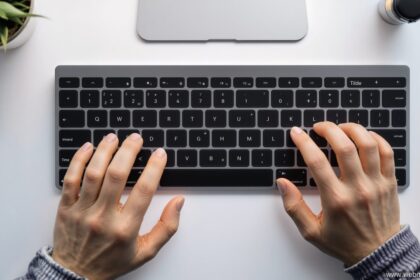 Tilde Mac Tastatur – Finger auf Apple Magic Keyboard beim Eingeben des Tilde-Zeichens